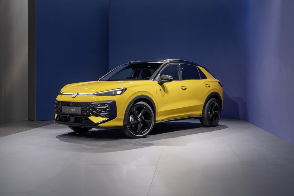 VW T-Roc 2025 Frontansicht in Gelb vor moderner Architektur